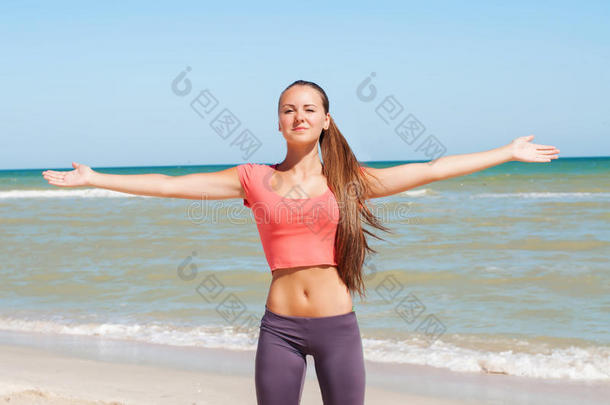 美丽的女孩正在海滩上练瑜伽