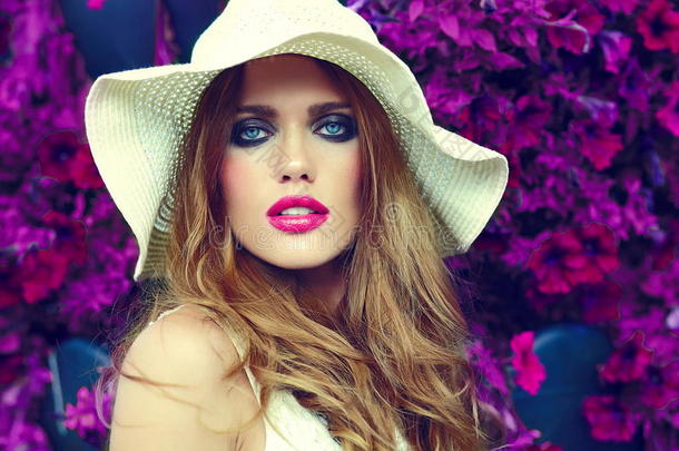 生活方式金发模特女孩戴帽子靠近花朵和粉色嘴唇