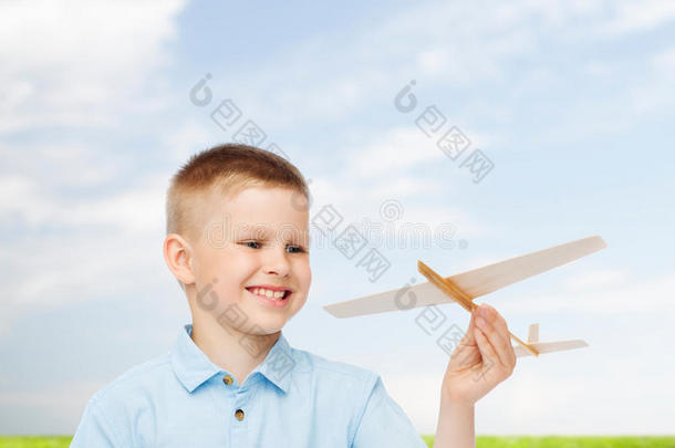 微笑的小男孩拿着一个木制飞机模型