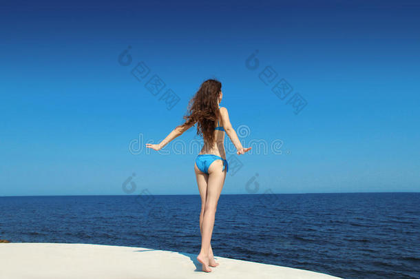 享受。在户外，穿着比基尼比基尼的自由黑发模特。黑发女孩在海滩上放松。