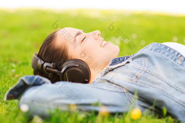 躺在草地上戴着耳机微笑的小女孩