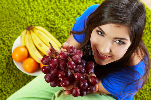 女人坐在地板上吃水果。