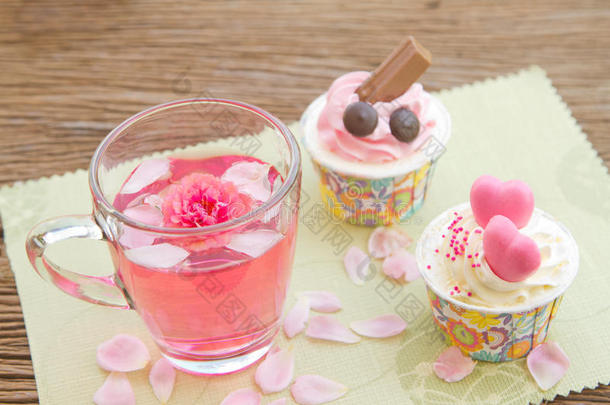 花园里的桌子上摆着玫瑰花茶和甜甜的纸杯蛋糕