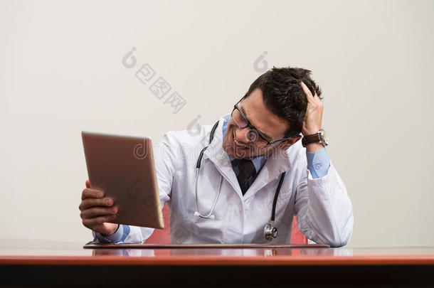 劳累过度的医生坐在他的办公桌旁