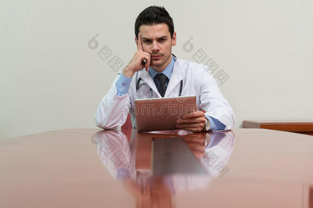 <strong>劳累过度</strong>的医生坐在他的办公桌旁
