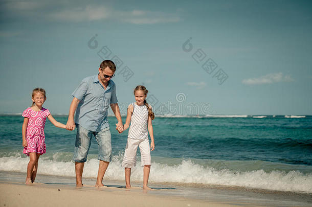 父亲和两个女儿在海滩上散步