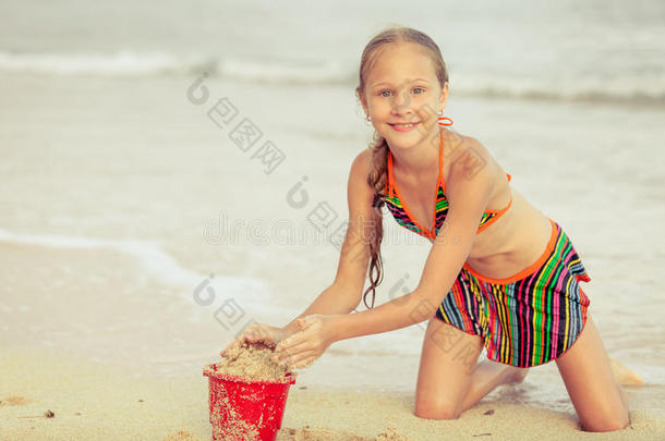 小女孩在沙滩上玩玩具沙子