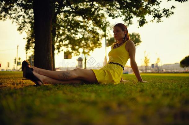 在夕阳的<strong>余晖</strong>中，穿着黄色连衣裙的美丽女孩坐在草地上