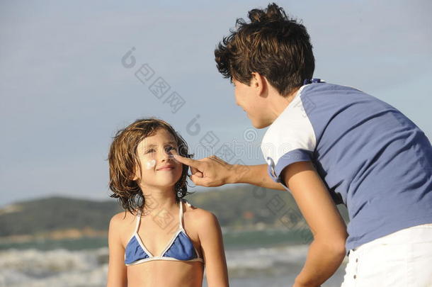 母亲在海滩给女儿涂防晒霜。