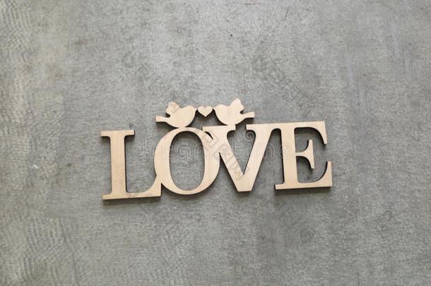 在灰色背景上用木头雕刻的刻有“爱”字样的牌匾