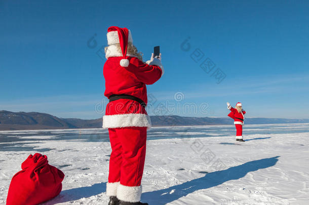 圣诞老人用另一个圣诞老人的智能手机拍照，走在