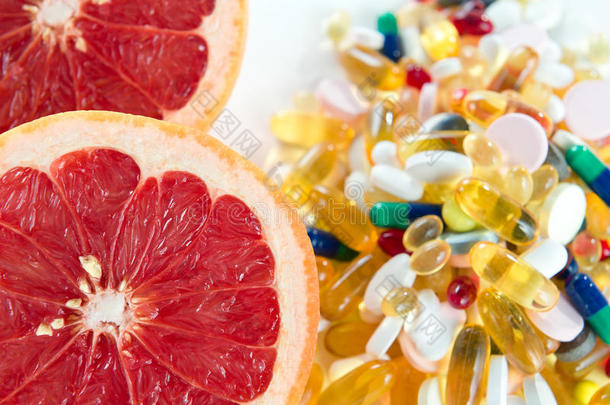 粉红葡萄柚和药丸，白底维生素补充剂，健康饮食理念