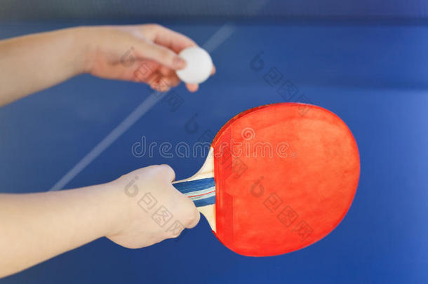 女孩用红色的球拍打乒乓球