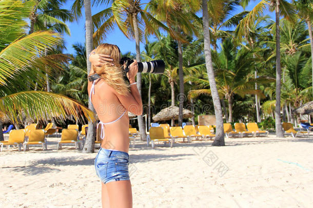 一个<strong>头发飘逸</strong>的女孩在海滩上拿着照相机
