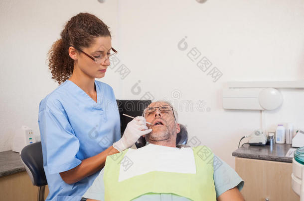 <strong>牙医</strong>坐在<strong>牙医</strong>椅上检查病人的牙齿
