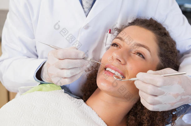 牙医坐在牙医椅上检查病人的牙齿