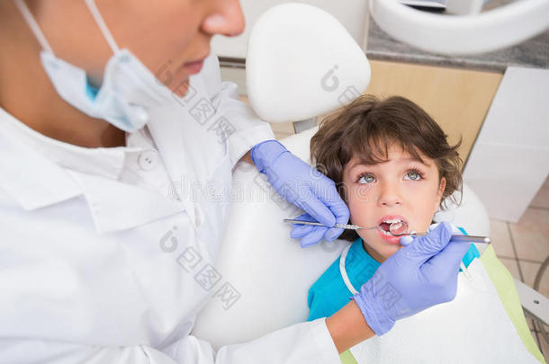 儿科<strong>牙医</strong>在<strong>牙医</strong>椅上检查一个小男孩的牙齿