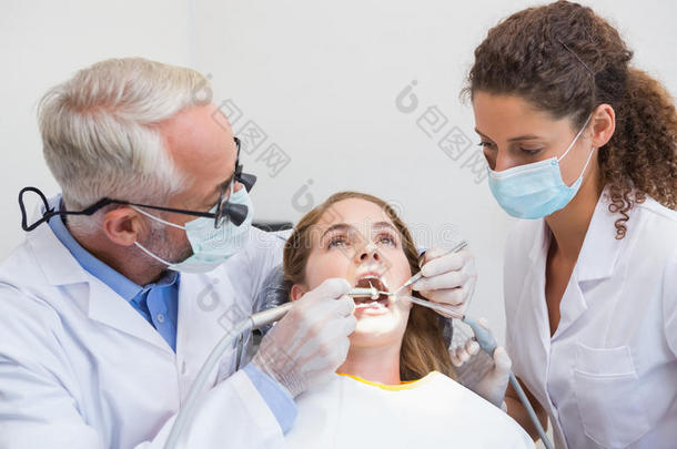 牙医和助手在牙医椅子上检查病人的牙齿