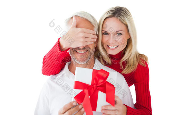 微笑的女人遮住伴侣的眼睛，拿着礼物