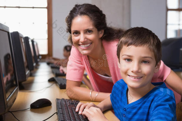 可爱的小学生和老师一起上电脑课
