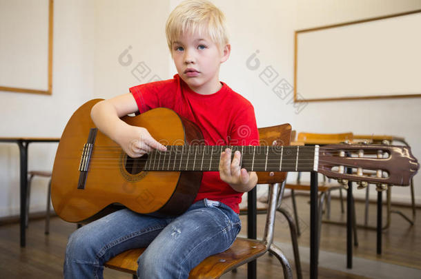可爱的学生在教室里弹吉他