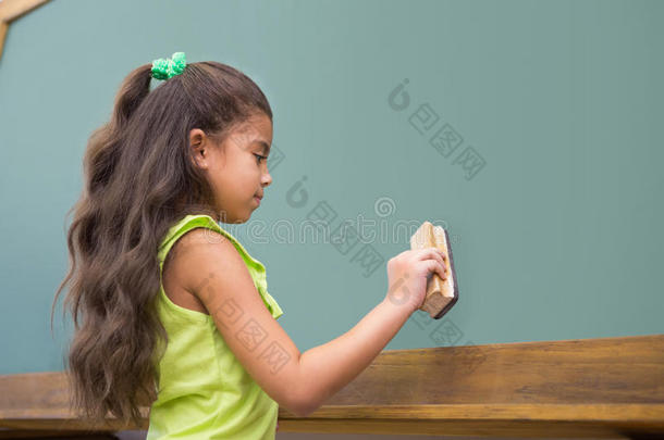 可爱的小学生站在教室里擦黑板