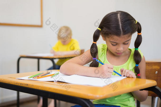 可爱的小学生在教室的课桌前涂色