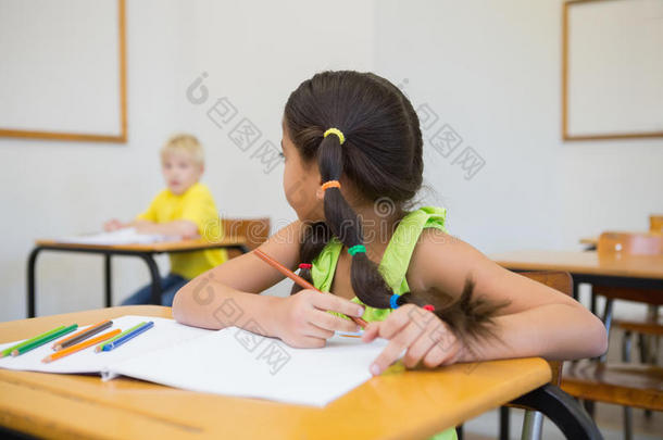 可爱的小学生在教室的课桌前涂色