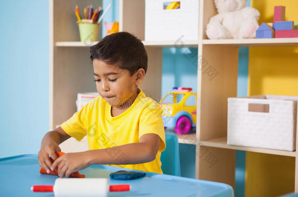 可爱的小男孩在教室里玩粘土模型