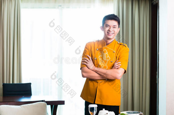亚洲中式客房服务生在酒店套房提供食物