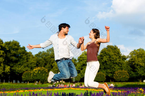 城市公园里的游客夫妇在阳光下跳跃