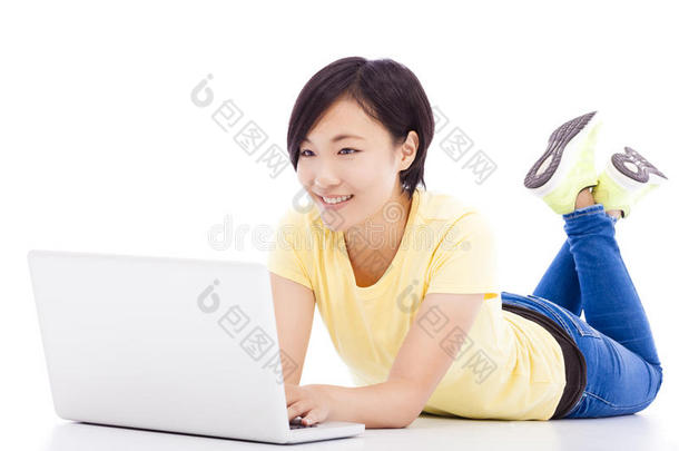快乐的女孩躺在地板上，手里拿着笔记本电脑