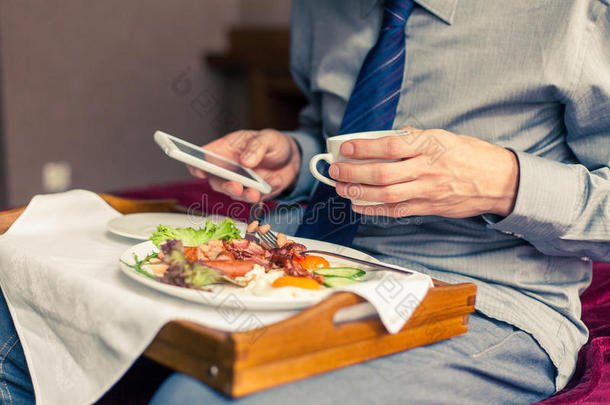 在家/酒店吃早餐时使用手机的商人。我