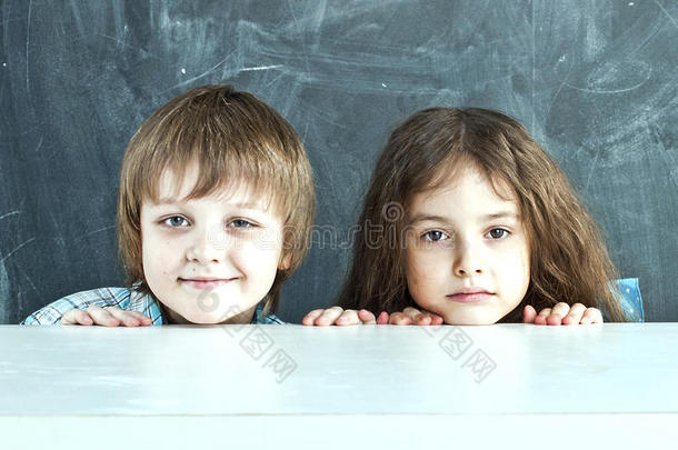 男孩和女孩躲在学校董事会附近的桌子后面