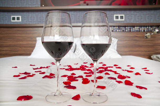 浪漫的卧室——床上摆着一杯红酒和玫瑰花瓣