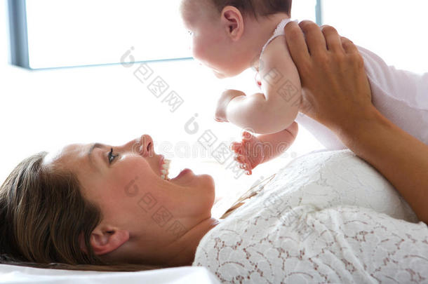 微笑的母亲抱着婴儿躺在床上