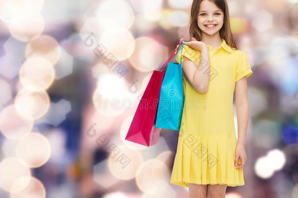 微笑的小女孩穿着衣服拿着购物袋