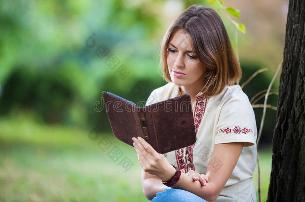 年轻漂亮的女人在公园里看电子书