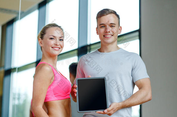 微笑的年轻女子和私人教练在健身房