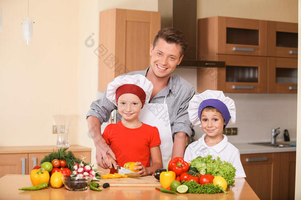 年轻的<strong>父亲教孩子</strong>们如何准备沙拉。