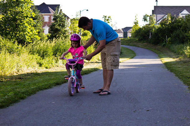 小女孩和她爸爸一起学骑自行车
