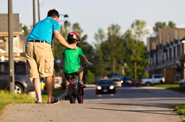 父亲帮助他的孩子骑自行车
