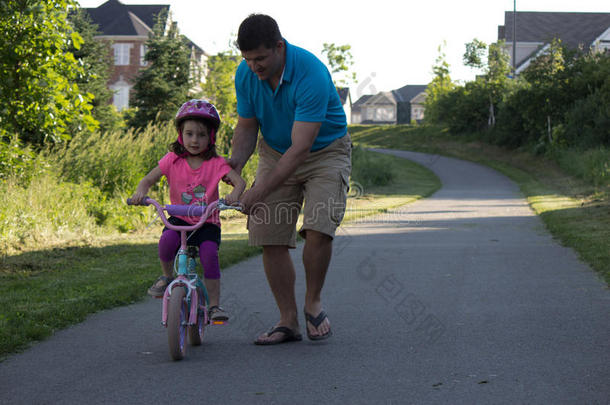 父亲帮助女儿骑自行车