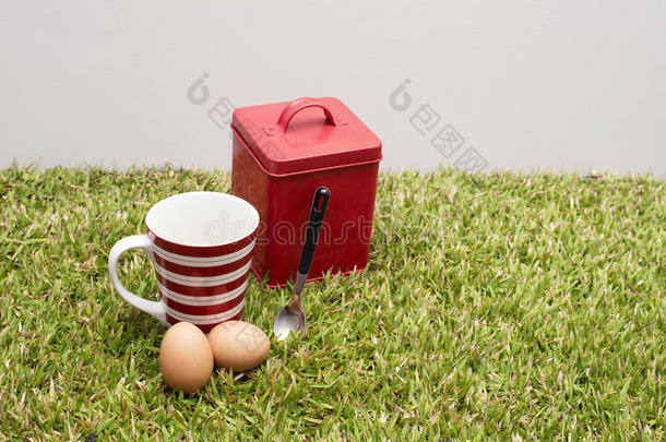 红罐头，咖啡杯，两个鸡蛋和一个勺子。
