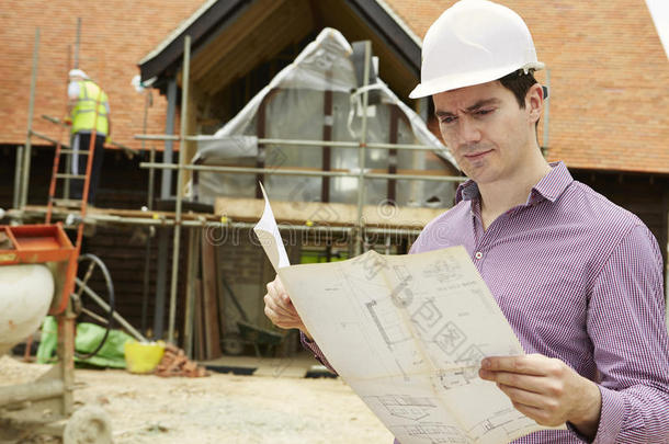 建筑师在工地上看房子平面图