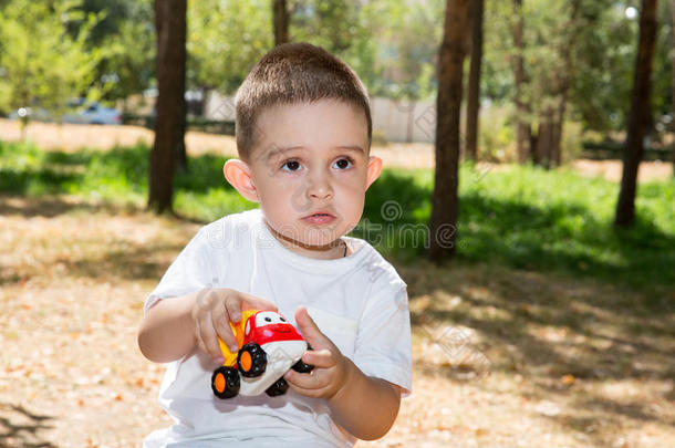 夏天，可爱的小男孩在公园里玩玩具车。