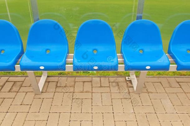 <strong>室外</strong>运动场球员长凳上的新蓝色塑料<strong>座椅</strong>，透明弯曲塑料屋顶下的椅子涂上新油漆。
