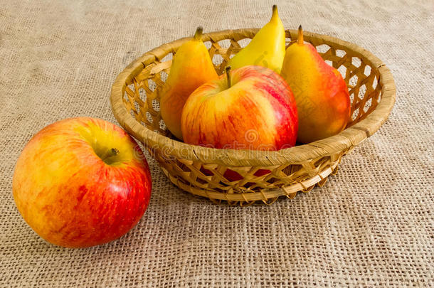 新鲜的红苹果和梨放在草篮里