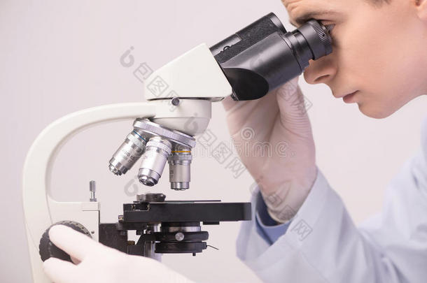在实验室用显微镜工作的男科学家。