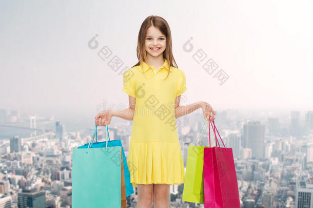 微笑的小女孩穿着衣服拿着购物袋